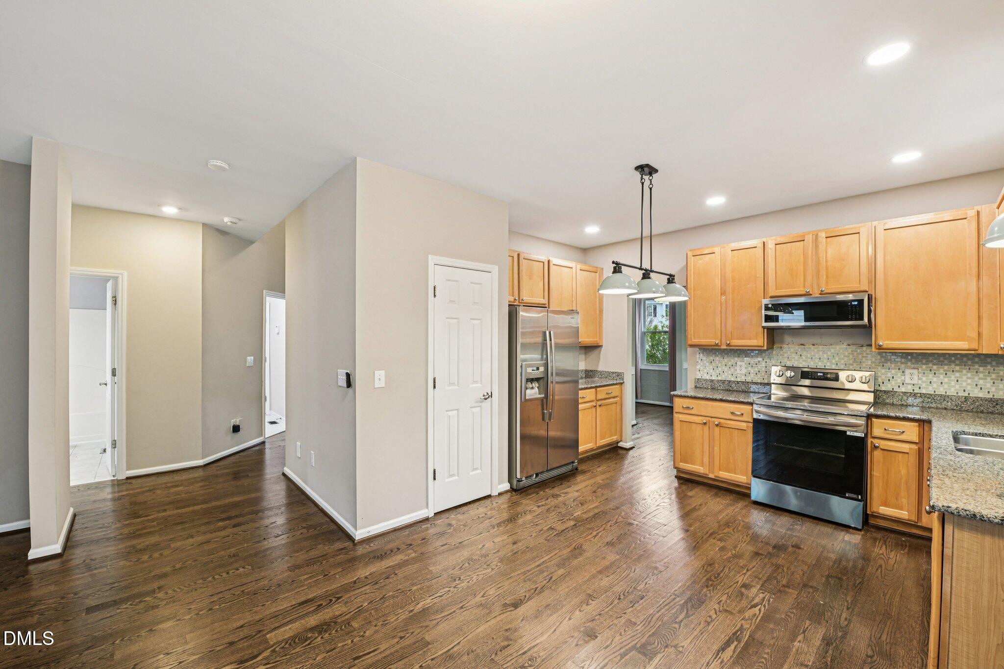 13100 Townfield Drive Raleigh, NC 27614 - Photo 8 of 31 a kitchen with stainless steel appliances granite countertop a refrigerator a sink a stove and oven with wooden floor