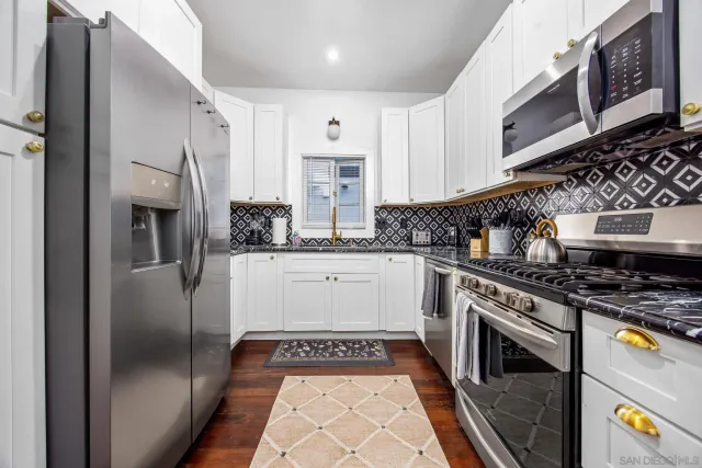 a kitchen with stainless steel appliances granite countertop a refrigerator a stove and a sink