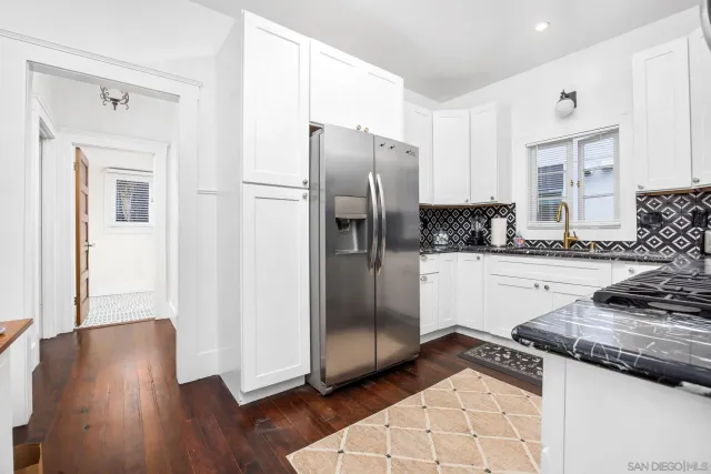 a kitchen with granite countertop a refrigerator and a stove top oven