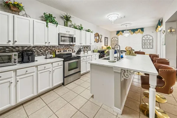 a kitchen with stainless steel appliances granite countertop a stove a sink dishwasher and white cabinets with wooden floor
