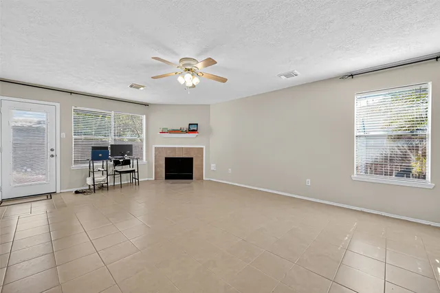 a view of a livingroom with a fireplace a ceiling fan and windows