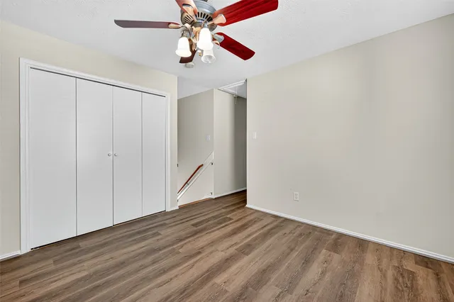 an empty room with wooden floor chandelier fan and windows