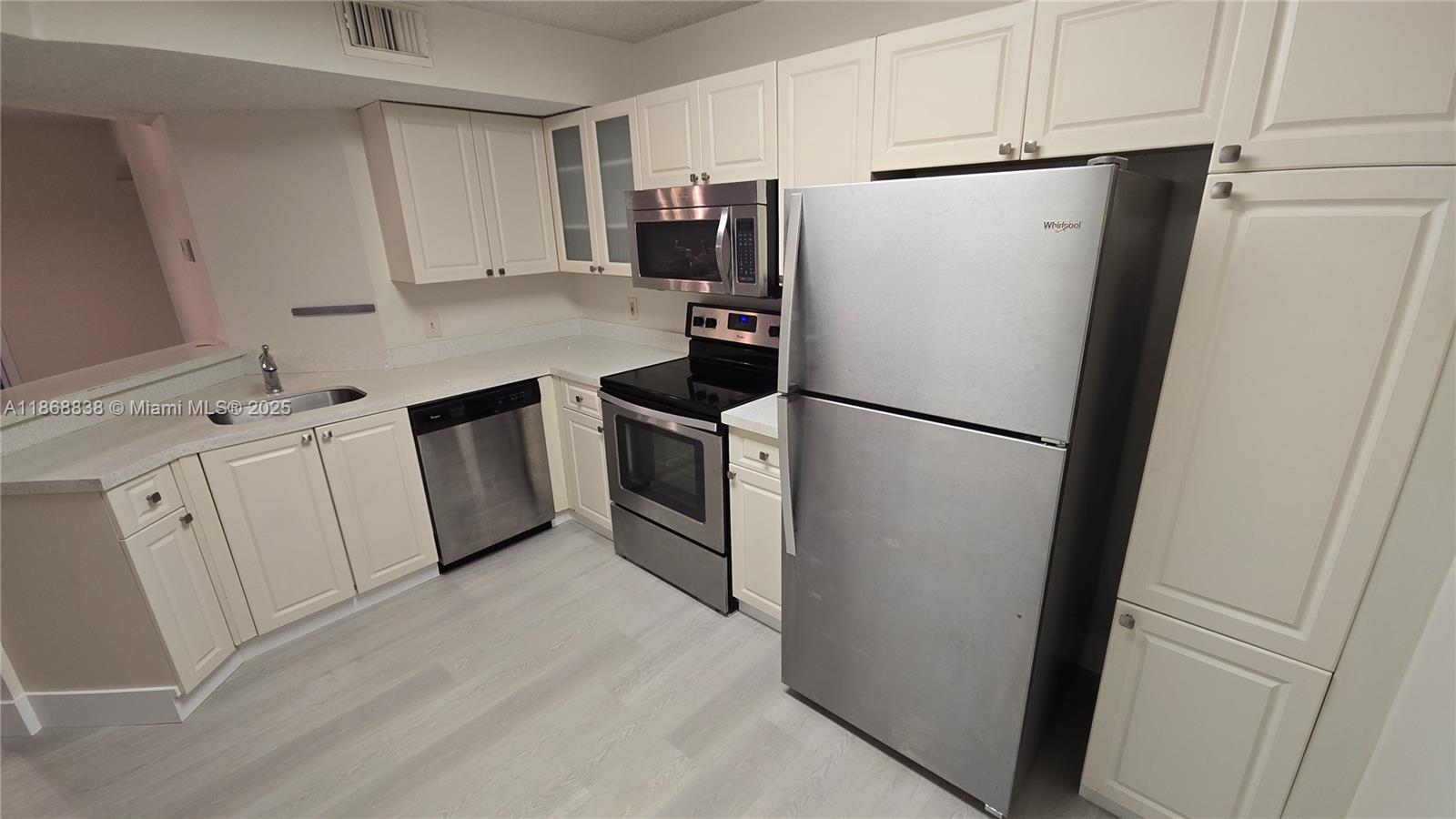 8851 Wiles Road, Unit 103 Coral Springs, FL 33067 - Photo 6 of 23 a kitchen with stainless steel appliances a refrigerator a sink and white cabinets