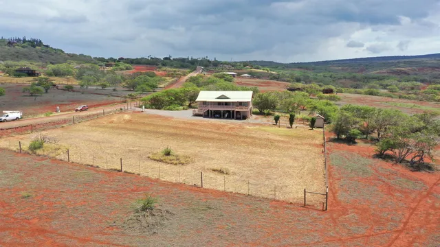 an aerial view of a house with big yard and large trees