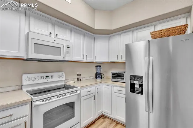a kitchen with stainless steel appliances white cabinets and a refrigerator