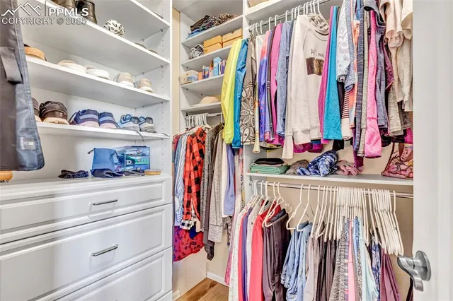 a view of walk in closet with clothes and shoes