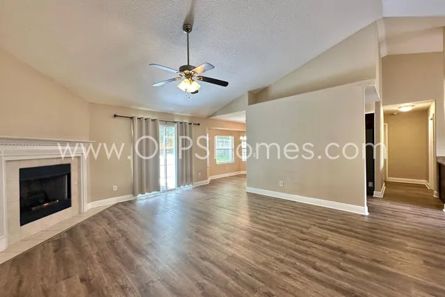 a view of an empty room with wooden floor and a fireplace