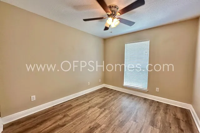 an empty room with wooden floor and fan