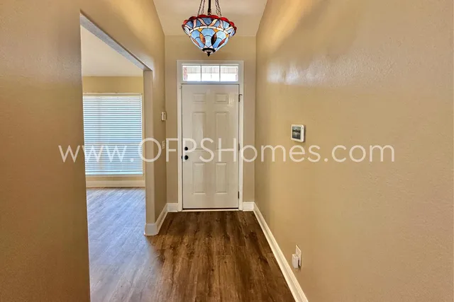 a view of a hallway with wooden floor and a bathroom