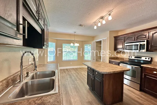 a kitchen with stainless steel appliances granite countertop a sink a stove and a wooden floors