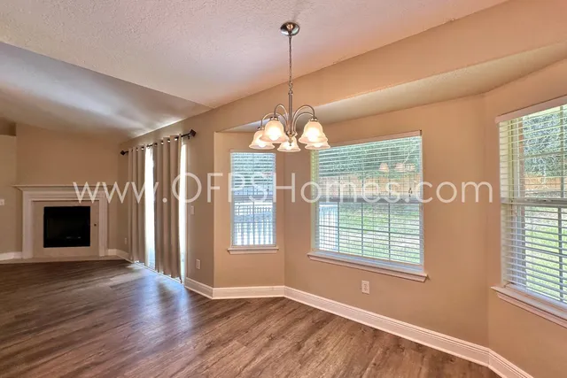 a view of a room with wooden floor fireplace and windows