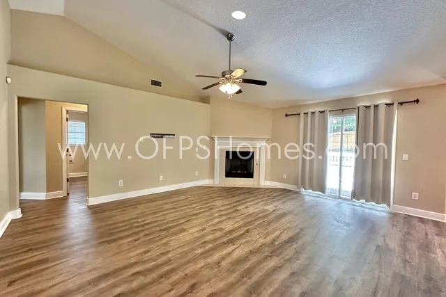 a view of an empty room with a fireplace and a window