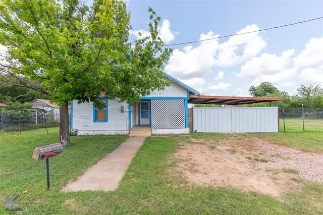 a view of a house with a yard and a large tree