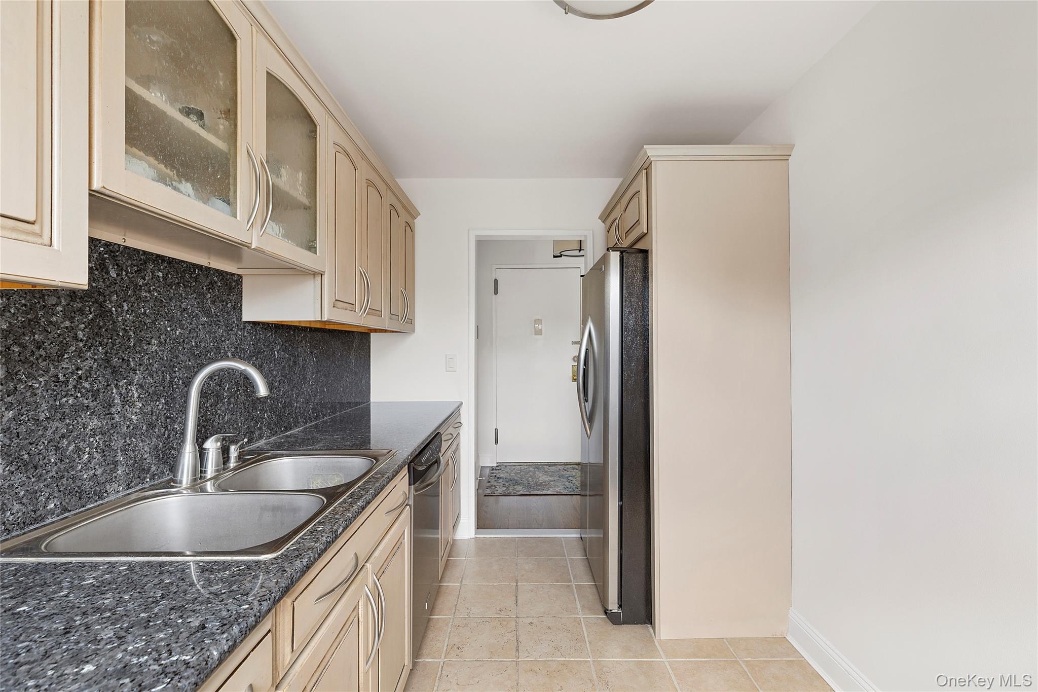 21 Chapel Place, Unit 3M Great Neck, NY 11021 - Photo 8 of 21 Kitchen featuring glass insert cabinets, light tile patterned floors, stainless steel appliances, decorative backsplash, and cream cabinets
