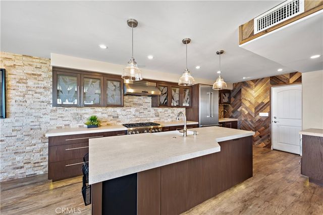 a kitchen with stainless steel appliances granite countertop a sink a stove and a wooden floors