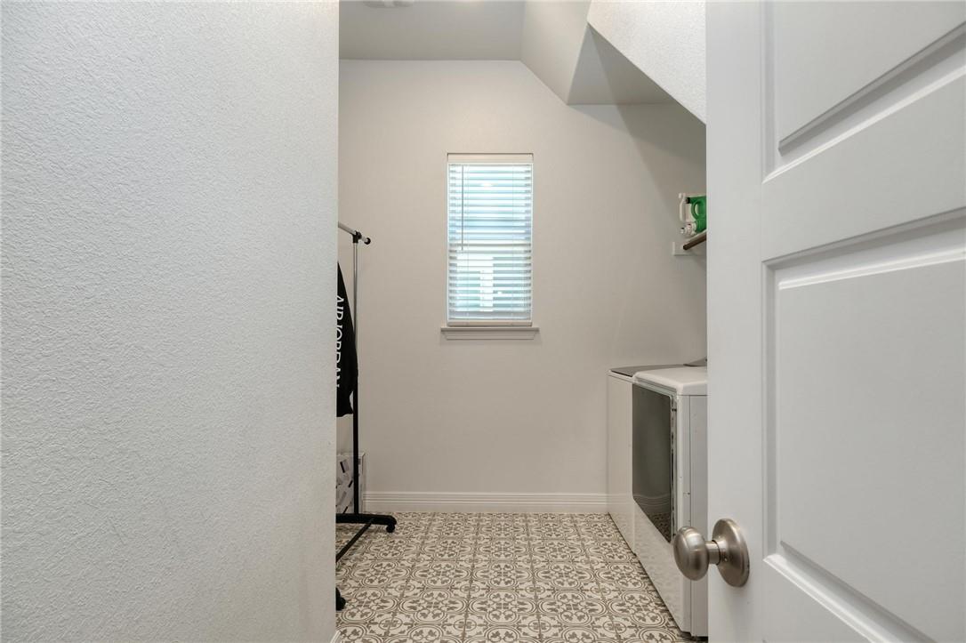 229 Bonnet Boulevard Georgetown, TX 78628 - Photo 18 of 20 Laundry room featuring washer and clothes dryer, light floors, and vaulted ceiling