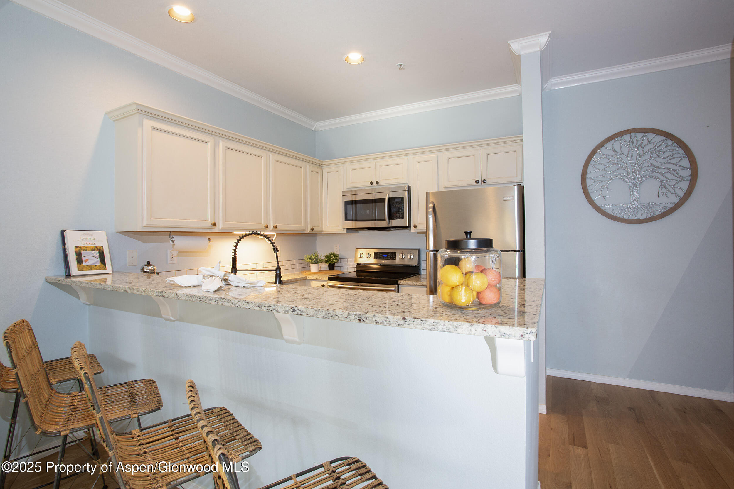 1400 East Valley Road, Unit 212 Basalt, CO 81621 - Photo 2 of 15 a kitchen with stainless steel appliances granite countertop a stove top oven a sink a dining table and chairs with wooden floor
