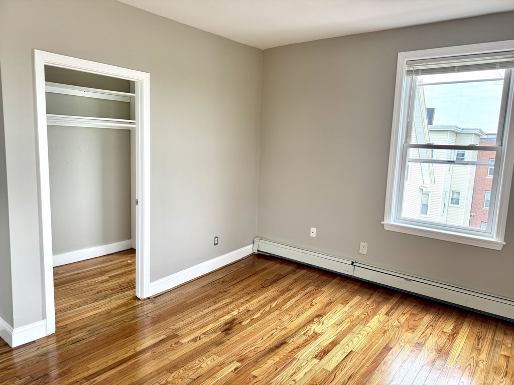 56 Estes Street, Unit 5 Lynn, MA 01902 - Photo 5 of 11 an empty room with wooden floor and windows