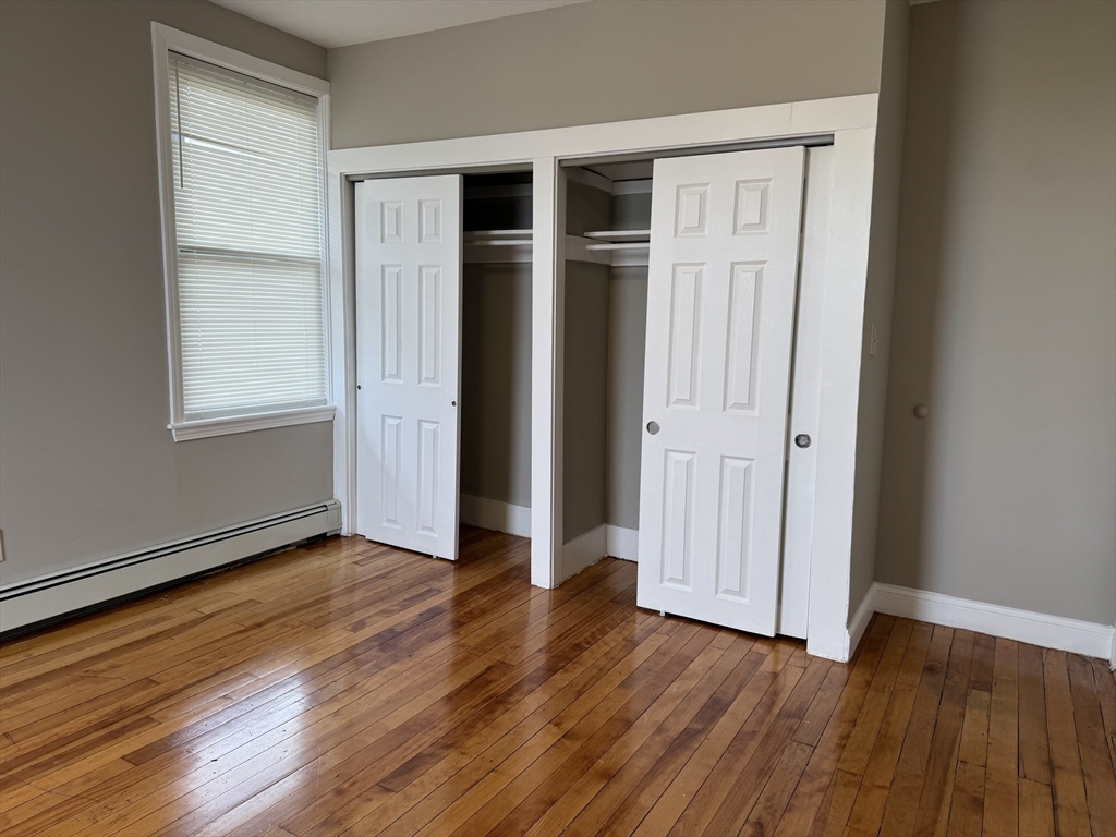 56 Estes Street, Unit 5 Lynn, MA 01902 - Photo 9 of 11 an empty room with wooden floor and windows