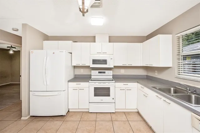 a white kitchen with a stove a refrigerator and white cabinets