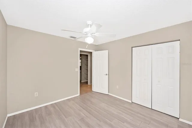 an empty room with a window and a ceiling fan