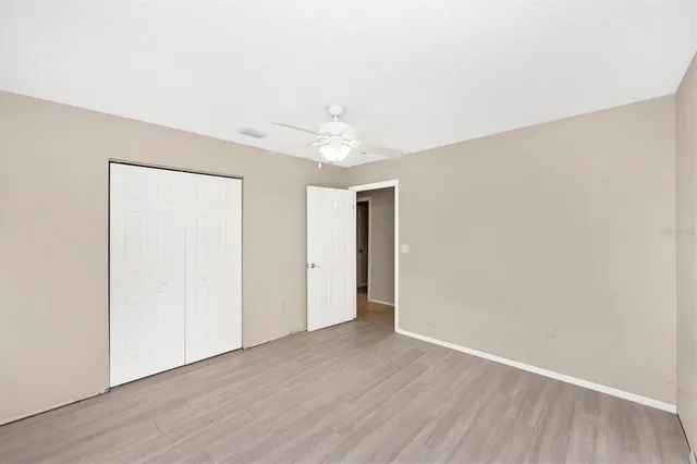 an empty room with wooden floor and a ceiling fan