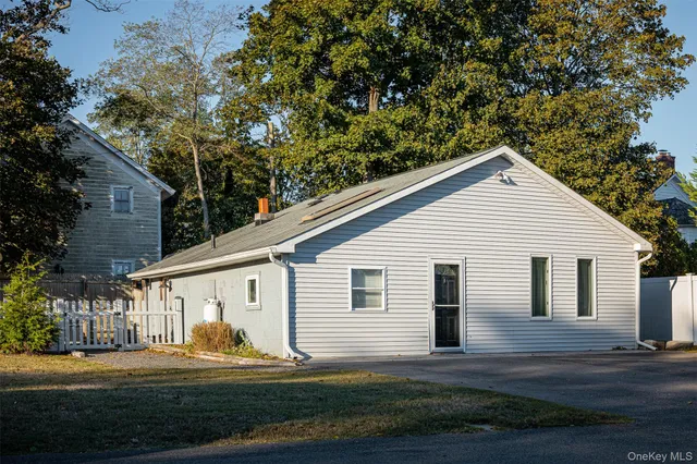 a view of a white house next to a yard with big trees