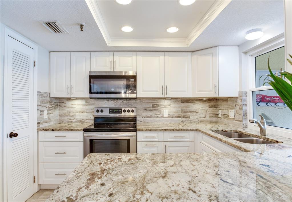 17450 Gulf Boulevard, Unit 206 Redington Shores, FL 33708 - Photo 25 of 52 a kitchen with granite countertop a stove sink and microwave