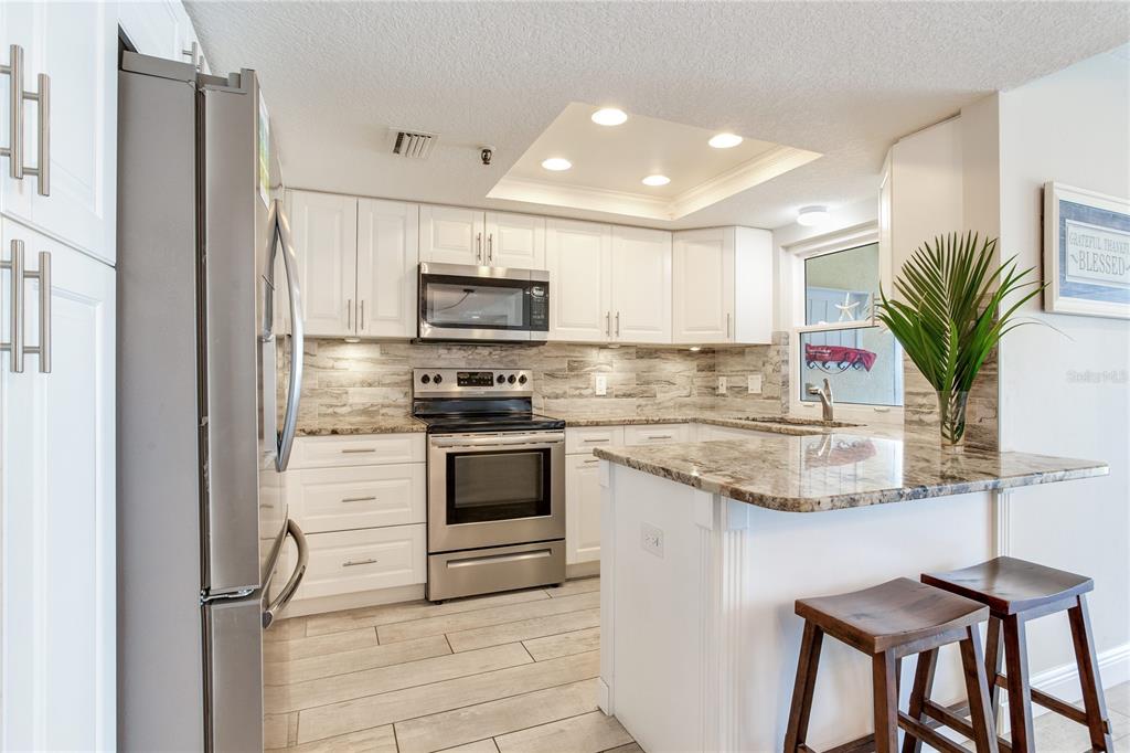 17450 Gulf Boulevard, Unit 206 Redington Shores, FL 33708 - Photo 26 of 52 a kitchen with stainless steel appliances granite countertop a stove a sink and a refrigerator