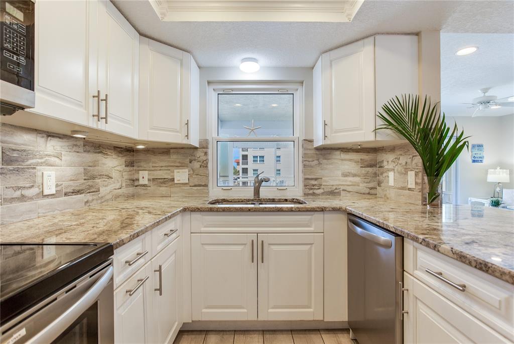 17450 Gulf Boulevard, Unit 206 Redington Shores, FL 33708 - Photo 28 of 52 a kitchen with granite countertop a sink and cabinets