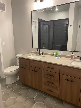 a bathroom with a granite countertop toilet sink and mirror