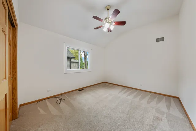 an empty room with windows and ceiling fan