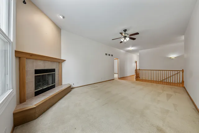 a view of an empty room with a fireplace and a ceiling fan