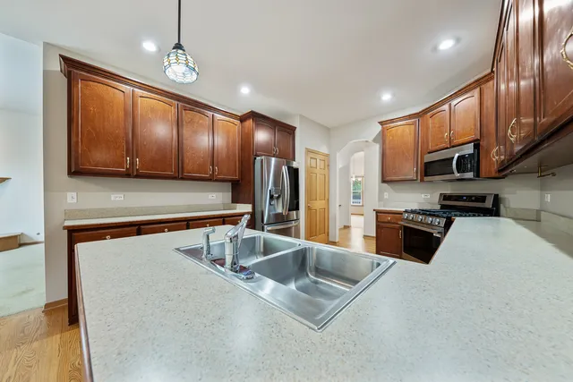 a large kitchen with stainless steel appliances wooden cabinets a stove a sink and a refrigerator