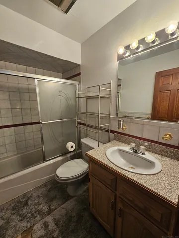 a bathroom with a sink a toilet a mirror and shower