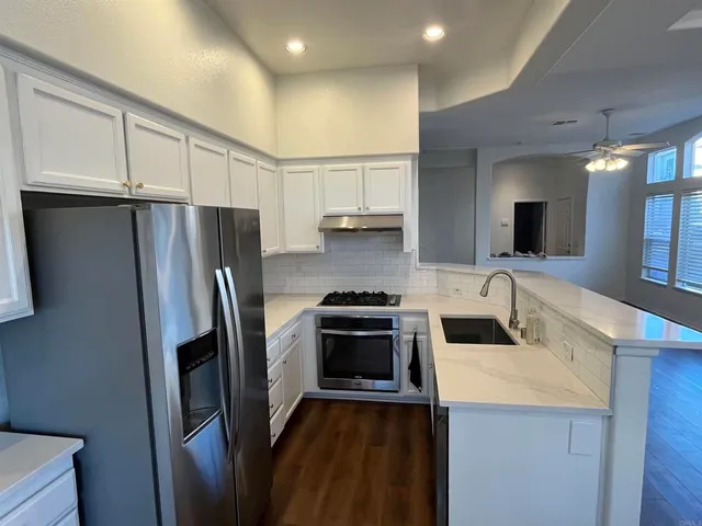 a kitchen with a refrigerator a stove a sink and dishwasher with wooden floor