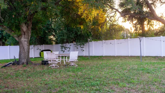 a view of backyard with wooden fence and a large tree