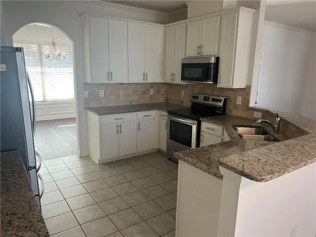 a kitchen with granite countertop a stove a sink and a microwave