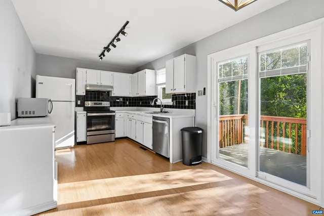 a kitchen with stainless steel appliances granite countertop a stove a sink dishwasher a refrigerator and a dining table with wooden floor