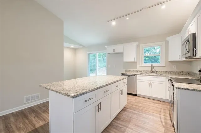 a kitchen with granite countertop white cabinets and window
