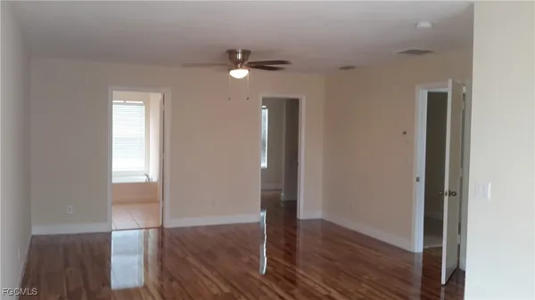 an empty room with wooden floor mirror and windows