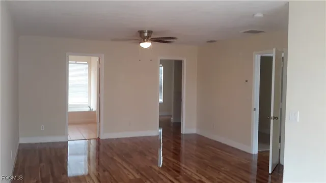 an empty room with wooden floor mirror and windows
