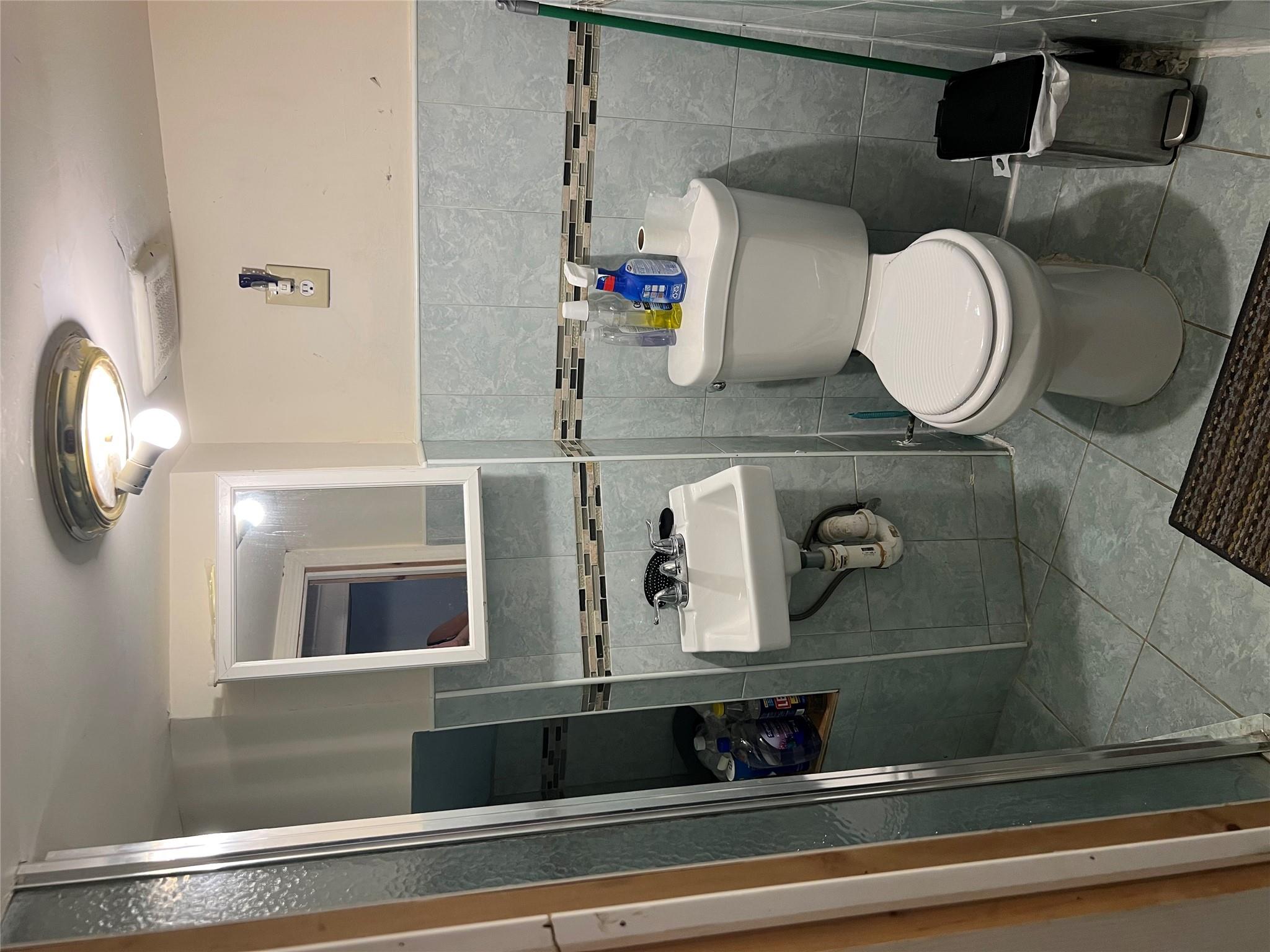 90-28 78th Street Queens, NY 11421 - Photo 13 of 14 Half bath featuring tile patterned floors, tile walls, and a wainscoted wall