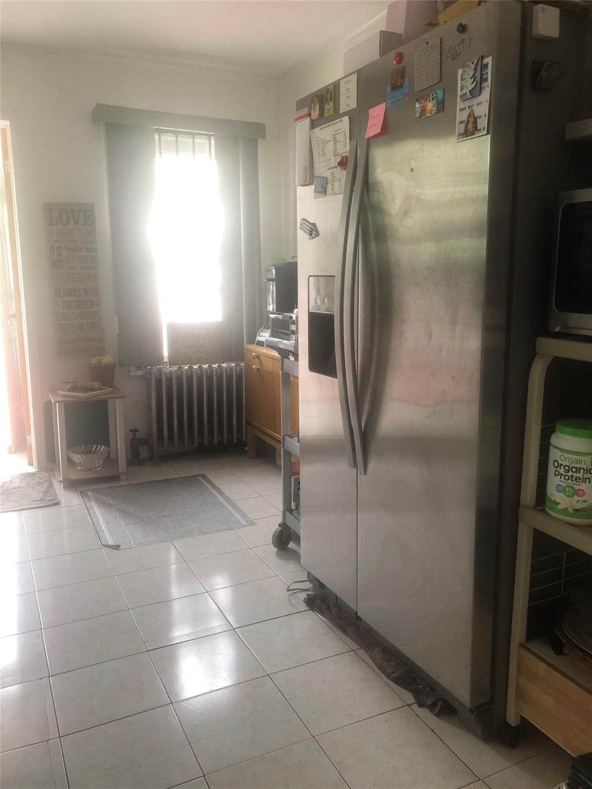 90-28 78th Street Queens, NY 11421 - Photo 3 of 14 Kitchen with appliances with stainless steel finishes, radiator heating unit, and light tile patterned floors
