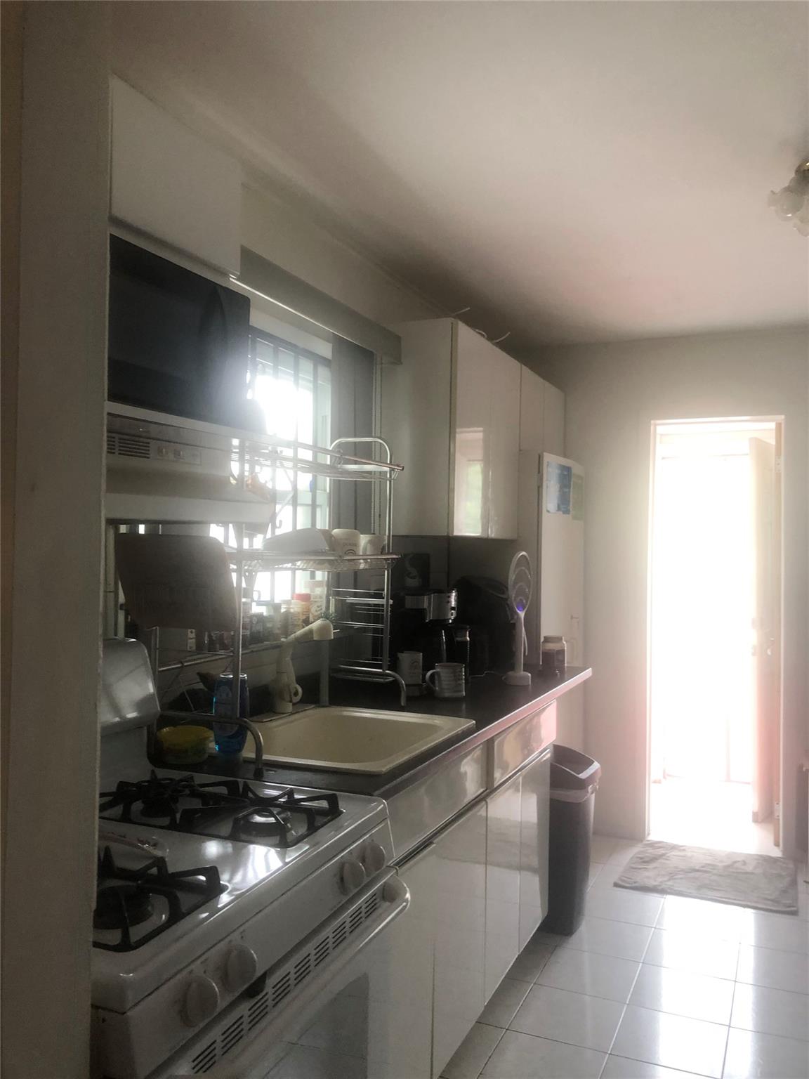 90-28 78th Street Queens, NY 11421 - Photo 4 of 14 Kitchen featuring gas range gas stove, white cabinets, and light tile patterned floors