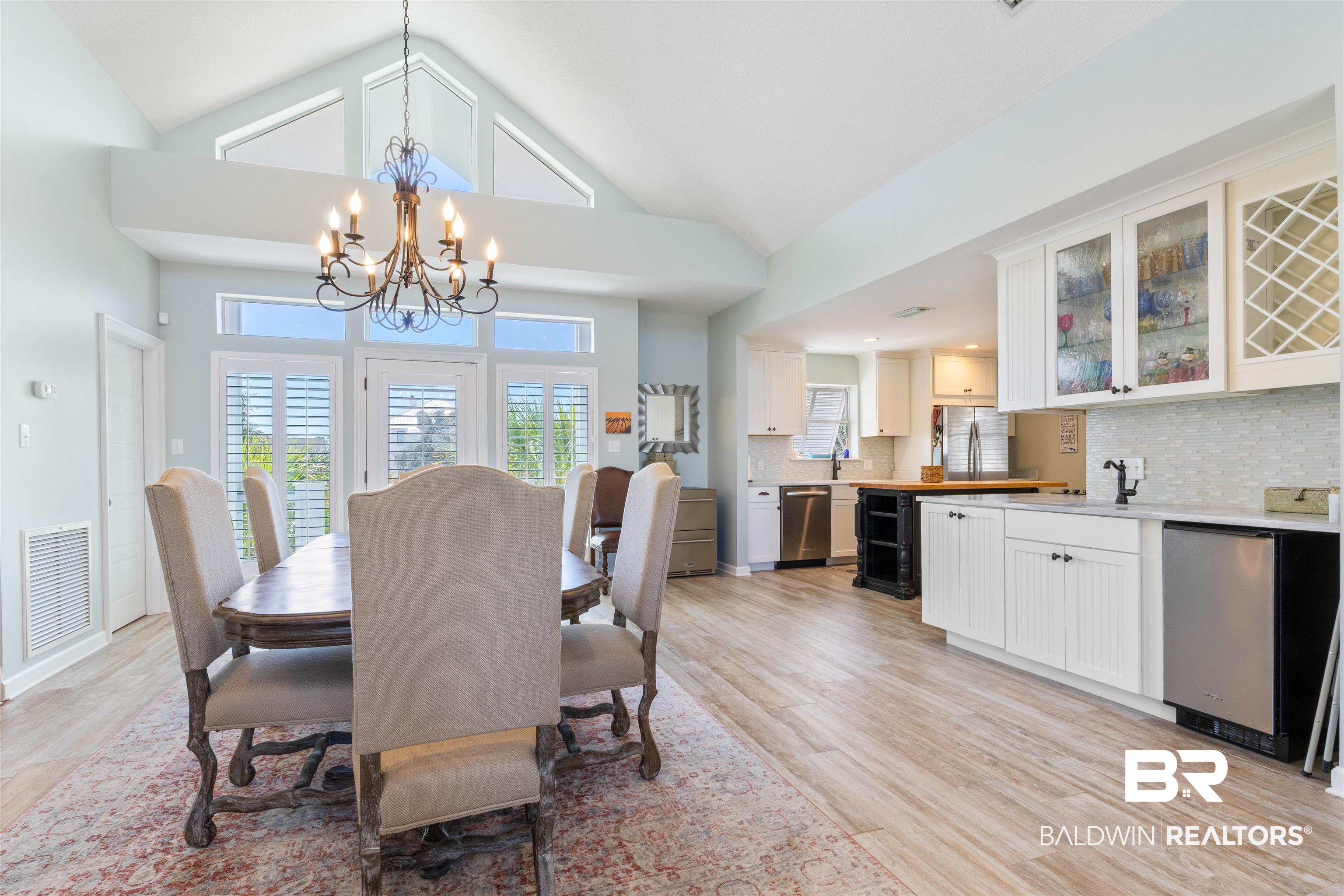 32315 River Road Orange Beach, AL 36561 - Photo 20 of 68 Dining space featuring a chandelier, light wood like tile flooring, and a high ceiling
