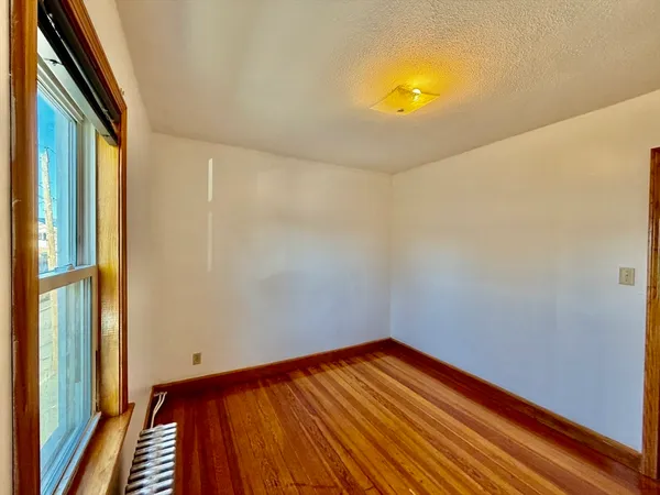 a view of a room with wooden floor and small window