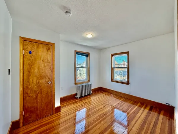 a view of an empty room with window and wooden floor