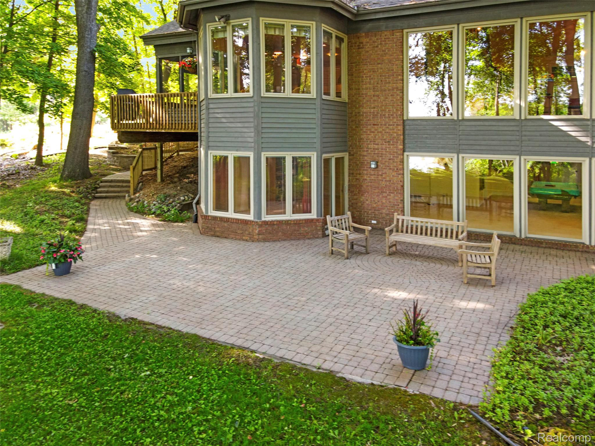 2323 Addaleen Road Highland, MI 48357 - Photo 14 of 70 Spacious paver patio with a curved border, surrounded by natural landscaping and mature trees