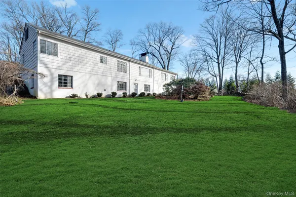 a view of a white house with a big yard and large trees